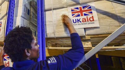 File photo dated August 2014 of logistics officer placing UK Aid stickers onto cargo pallets containing British aid items destined for areas suffering humanitarian crisis