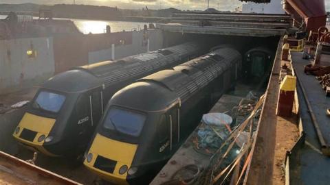 Two trains stationary on a large ship before transportation