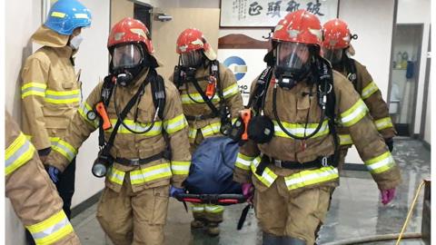 Firefighters carry a body bag on a stretcher out of the building in Daegu