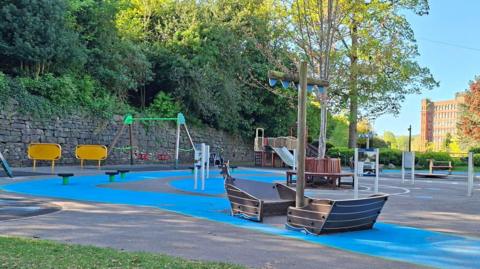 A play park with a boat frame in the middle