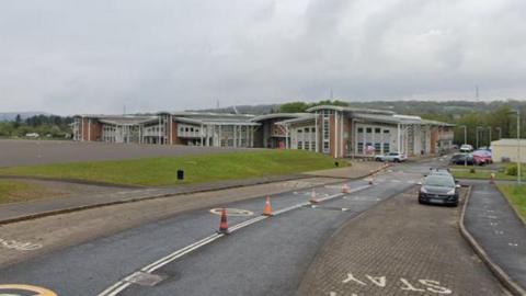 Ysgol Gyfun Gymraeg Rhydywaun is foregrounded by a road leading to it on the right and playgrounds on the left