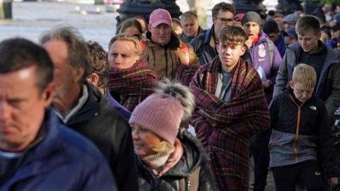 Members of the public queue between Westminster Bridge towards Lambeth Bridge in London