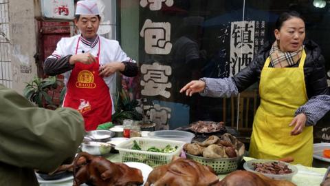 Chinese vendors sell cooked dog meat at a market in Guiyang, southern China's Guizhou province in December 2016