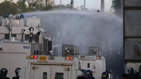 Police use a water canon on anti-immigrant protesters