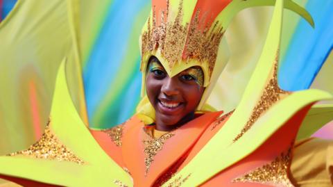 A girl smiling wearing a colourful costume. 