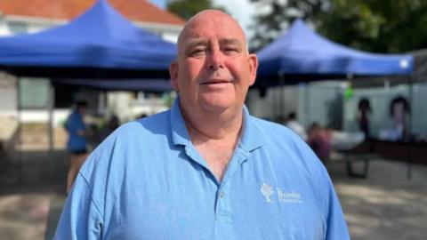 Man wearing blue T-shirt in front of charity stalls