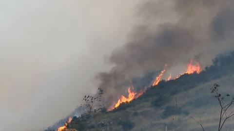 A fire burns on Arthur's Seat hill in Edinburgh. Smoke can be seen billowing from the orange flames.