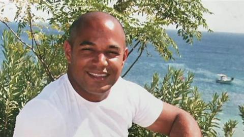 Archive image of Lee who is wearing a white t-shirt and sat in front of the sea.