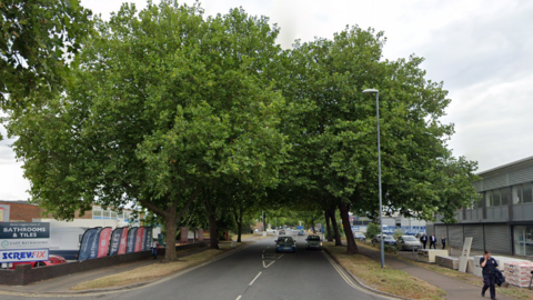 An industrial street with large trees on each side