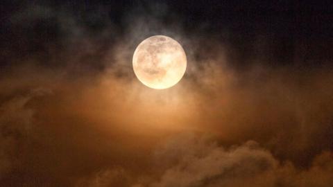 Atmospheric Moon peaking out amongst clouds