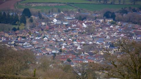 A picture of the view overlooking Tiverton. There is a large green space pictured around a number of houses.
