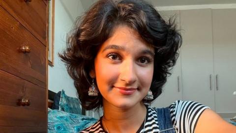 Girl with short dark hair looks at camera and smiles