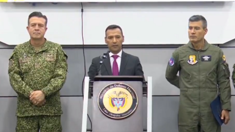 Colombian Defence Minister Pedro Sánchez speaks at a news conference. He is flanked by two high-ranking members of Colombia's military.
The minister is standing at a podium bearing the Ministry of Defence's official seal.