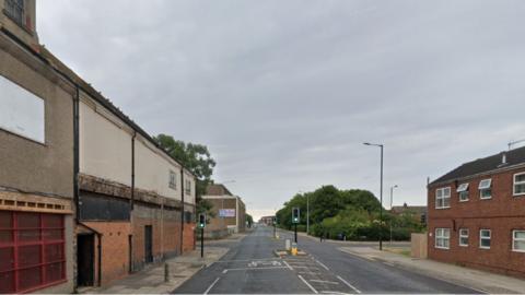 The junction of Oxford Street and Victor Street in Grimsby. It has a set of traffic lights and buildings on both side of the road.