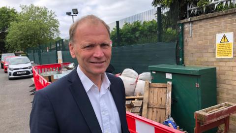 Adam Brewster, head of Heltwate School in Bretton, fly-tipping behind him.