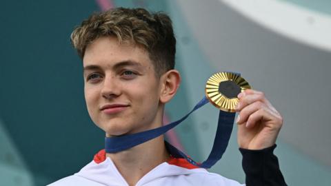 Toby Roberts holding up his Olympic gold medal.