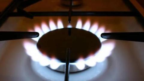 A closeup of a gas cooking hob with a white and red flame.