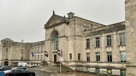 Exterior view of Southampton civic centre, a large cream brick building with a car park out the front