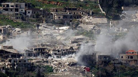 Smoke rises from bombed out buildings. 