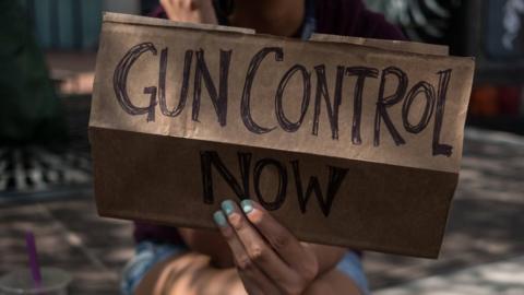 A woman holds a placard that say gun control now during a gun reform rally that was held in Dayton, Ohio in the wake of a mass shooting at the area earlier this month that left 9 dead and 27 wounded.