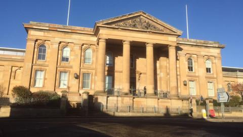 The exterior of a large court building with a blue sky above
