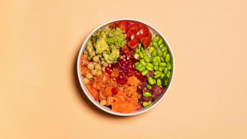 Aerial image of a bowl of colourful foods including edamame, carrot, kidney beans.
