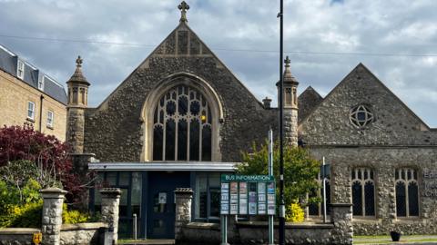 A church built with stone. There is a sign in front of the building.