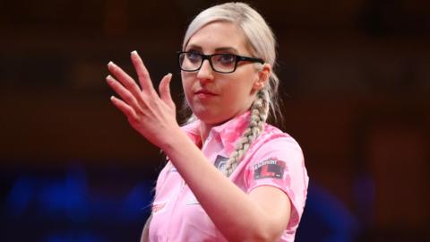 Fallon Sherrock waves her hand during a darts match