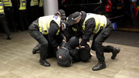 Police grapple with a protester on the ground