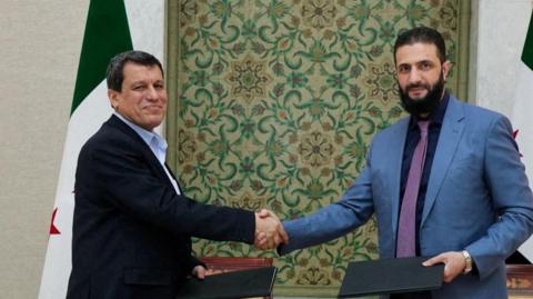 SDF commander Mazloum Abdi (L) shakes hands with interim Syrian President Ahmed al-Sharaa in Damascus on 10 March 2025