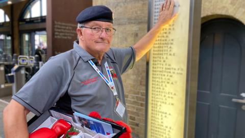 Denis Scaife touching the King's Cross station war memorial in London