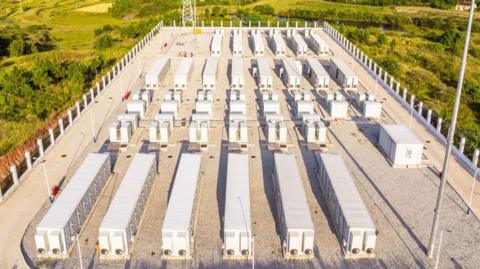 A battery storage facility, surrounded by green fields