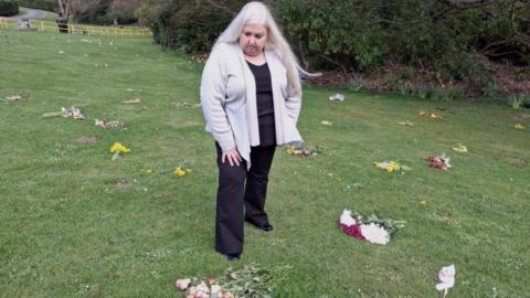 A woman with grey hair looking at flowers