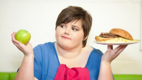 woman holding apple and burger