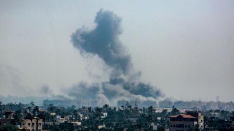 This picture taken from Deir al-Balah in the central Gaza Strip shows smoke billowing over the Hamad residential towers in Khan Younis following Israeli bombardment on 17 August 2024