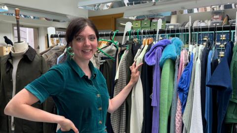 Costume designer standing by her costume rail. 