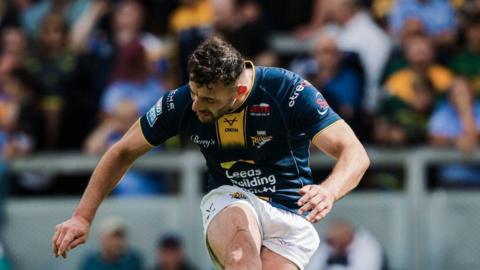 Leeds Rhinos' Jake Connor, with his head down, kicking a goal.