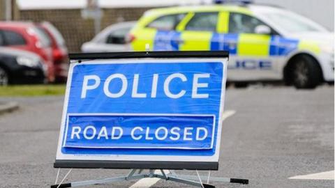 Road closed sign with police car behind