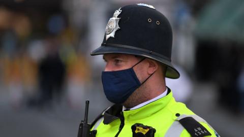 A police officer wearing a protective face covering patrols in Soho in London