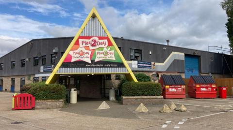 The outside of an industrial unit which is where Play2Day is based. A sign is above the entrance which says Play2Day on it. 