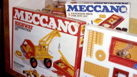 A collection of brightly coloured boxes of Meccano. 