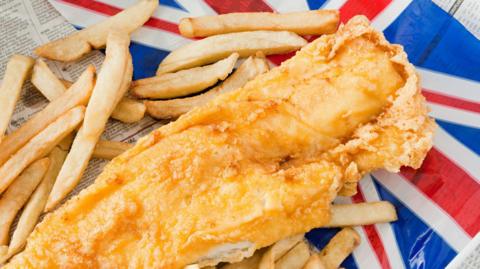 Portion of fish and chips on top of a red, white and blue Union flag