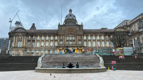 The Birmingham City Council building, as seen from below. The 'Floozie in the Jacuzzi' statue is in the middle of the picture, with steps on either side of her. Some construction work is visible at the top of the steps on the right.