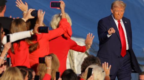 Trump gestures at the crowd while taking the stage in Butler