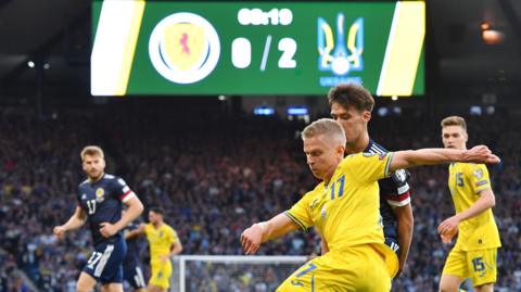 Oleksandr Zinchenko of Ukraine is challenged by Aaron Hickey of Scotland