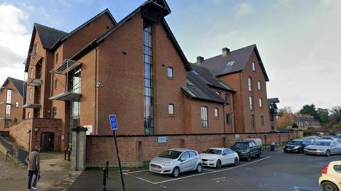 A large red brick building with cars parked outside