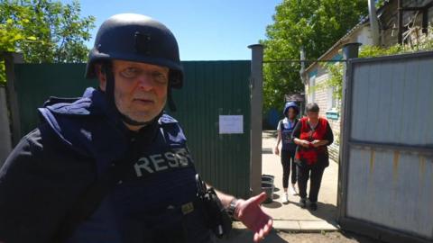 The 鶹Լ's Jeremy Bowen standing in front of woman being evacuated from her home