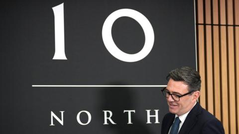 Andy Burnham next to a sign saying 10 North.
