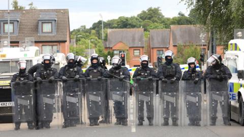 Riot police stand in a line in Belfast on August 3