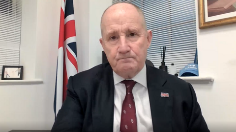 Kevin Hollinrake sitting in his office with a union flag in the background.